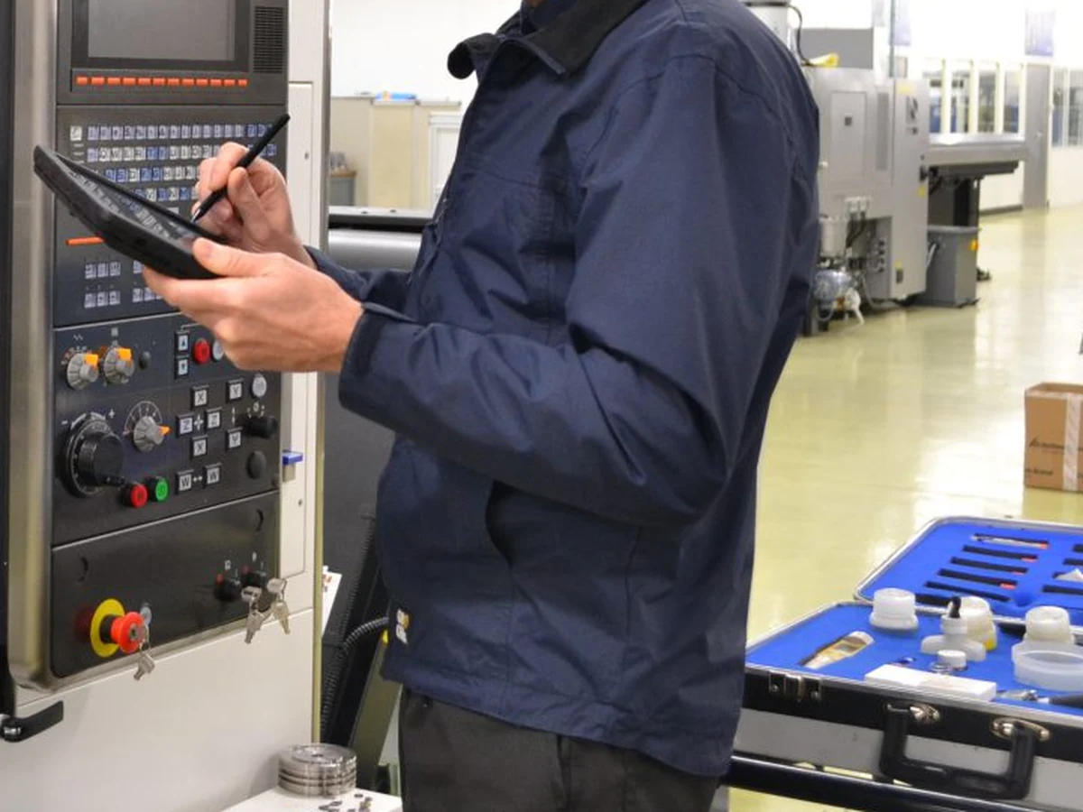 Monteur voert met meetapparatuur een meting uit naast een CNC-machine