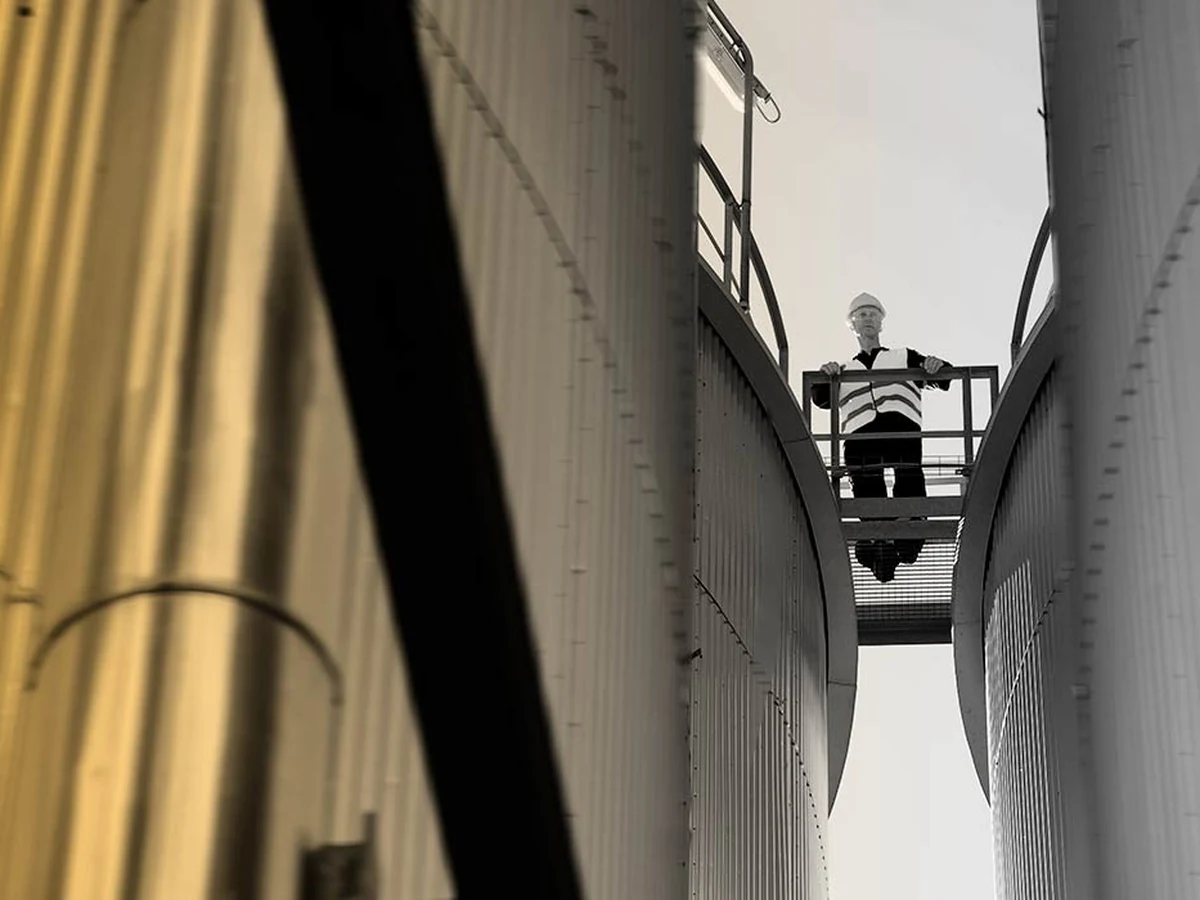 Medewerker met veiligheidshelm en beschermende kleding op een industriële installatie